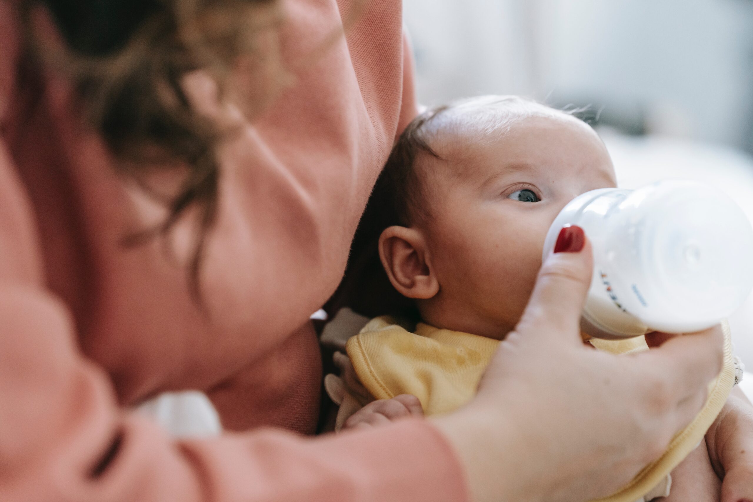 A parent bottle-feeding their baby