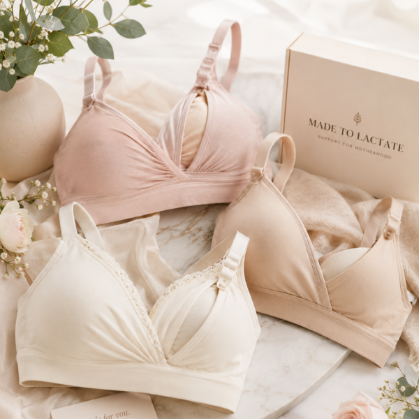 Three soft nursing bras in blush, cream and nude with drop-down clips, styled with eucalyptus and roses