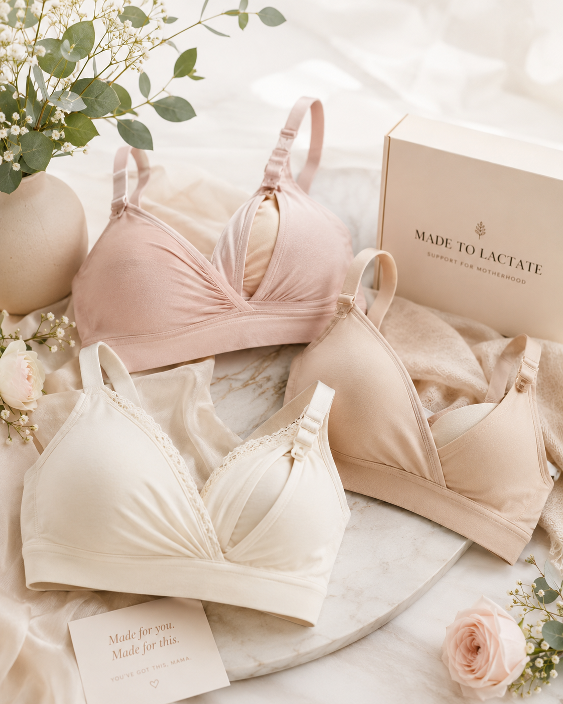 Three soft nursing bras in blush, cream and nude with drop-down clips, styled with eucalyptus and roses
